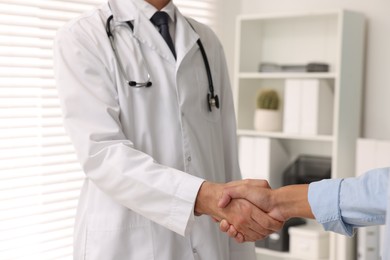 Doctor shaking hands with patient in hospital, closeup