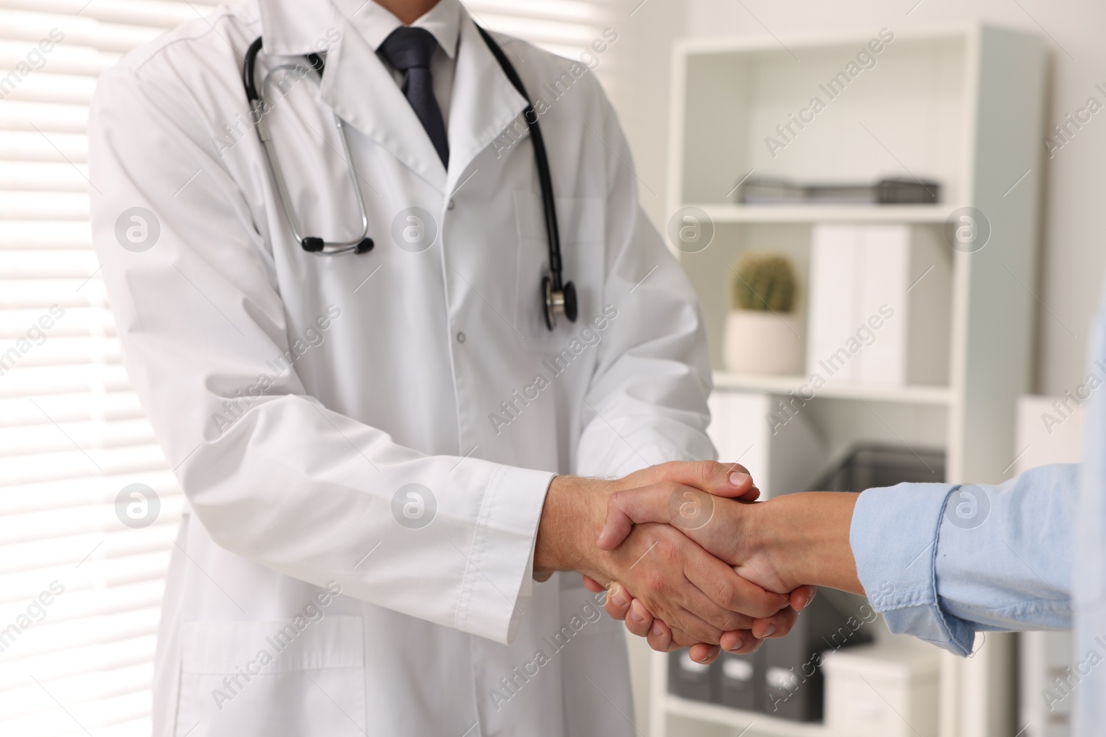 Photo of Doctor shaking hands with patient in hospital, closeup