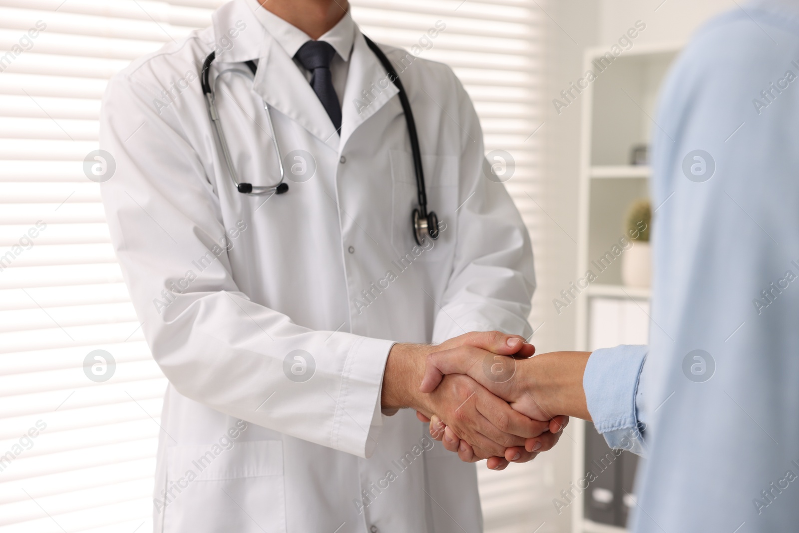 Photo of Doctor shaking hands with patient in hospital, closeup