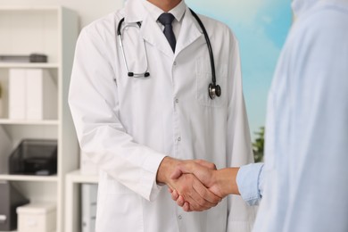 Photo of Doctor shaking hands with patient in hospital, closeup