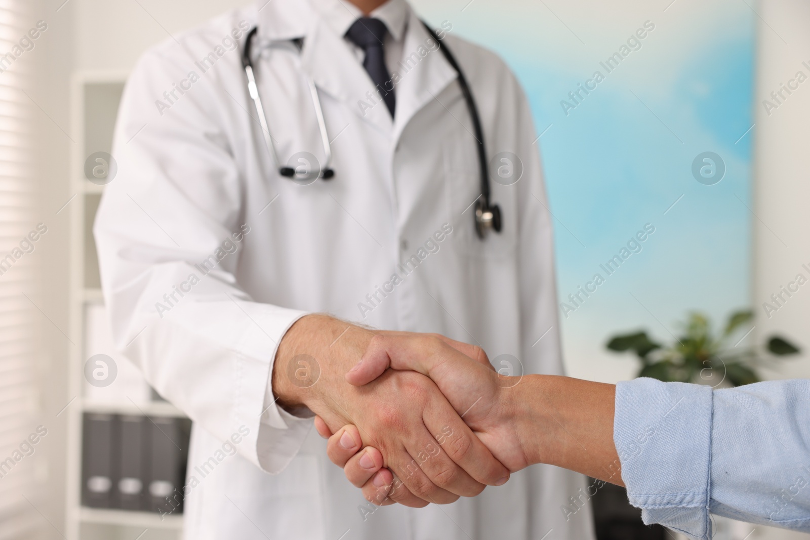 Photo of Doctor shaking hands with patient in hospital, closeup