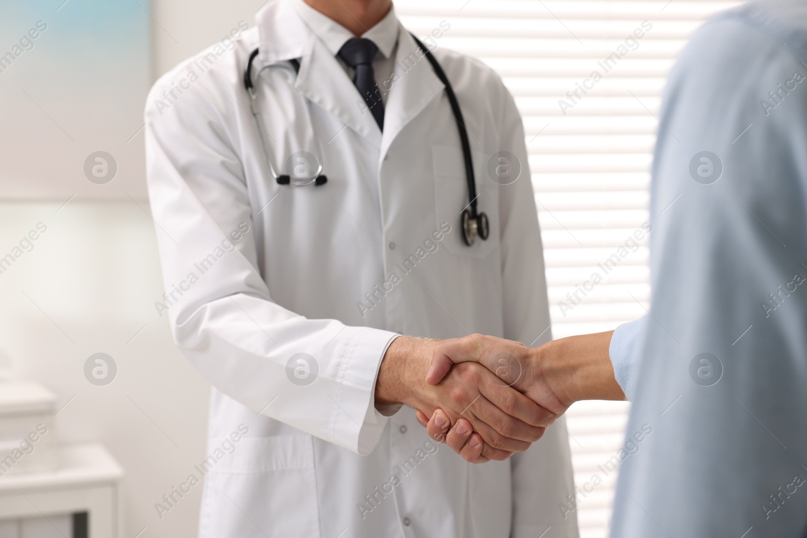 Photo of Doctor shaking hands with patient in hospital, closeup