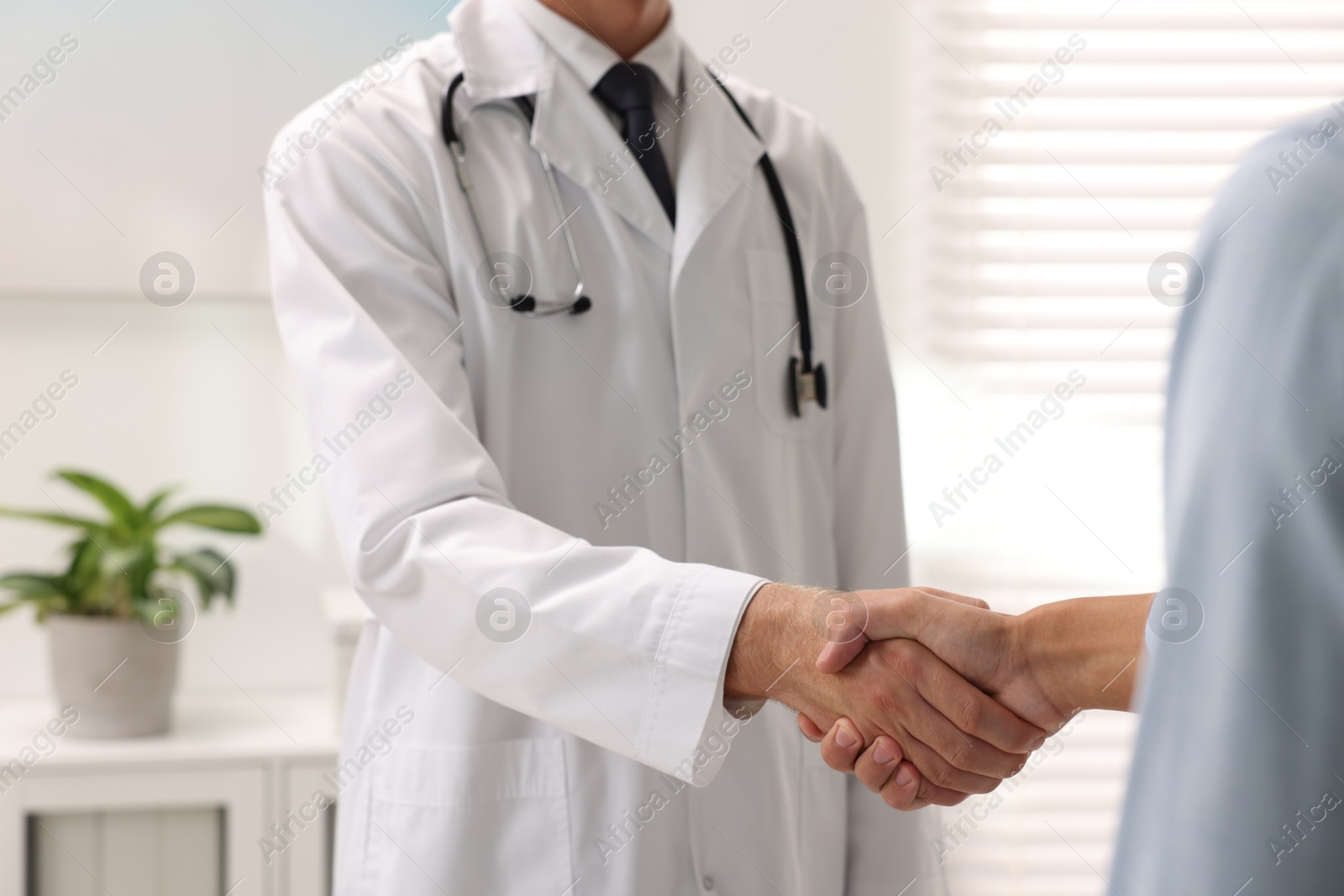 Photo of Doctor shaking hands with patient in hospital, closeup