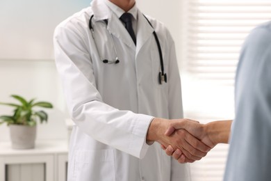 Doctor shaking hands with patient in hospital, closeup