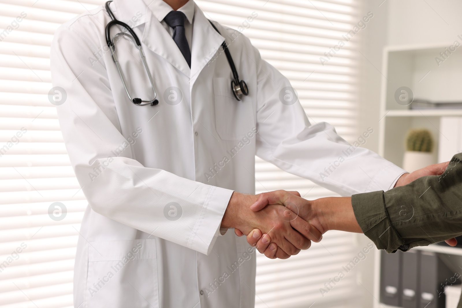 Photo of Doctor shaking hands with patient in hospital, closeup