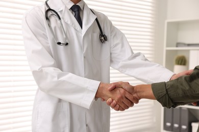 Doctor shaking hands with patient in hospital, closeup