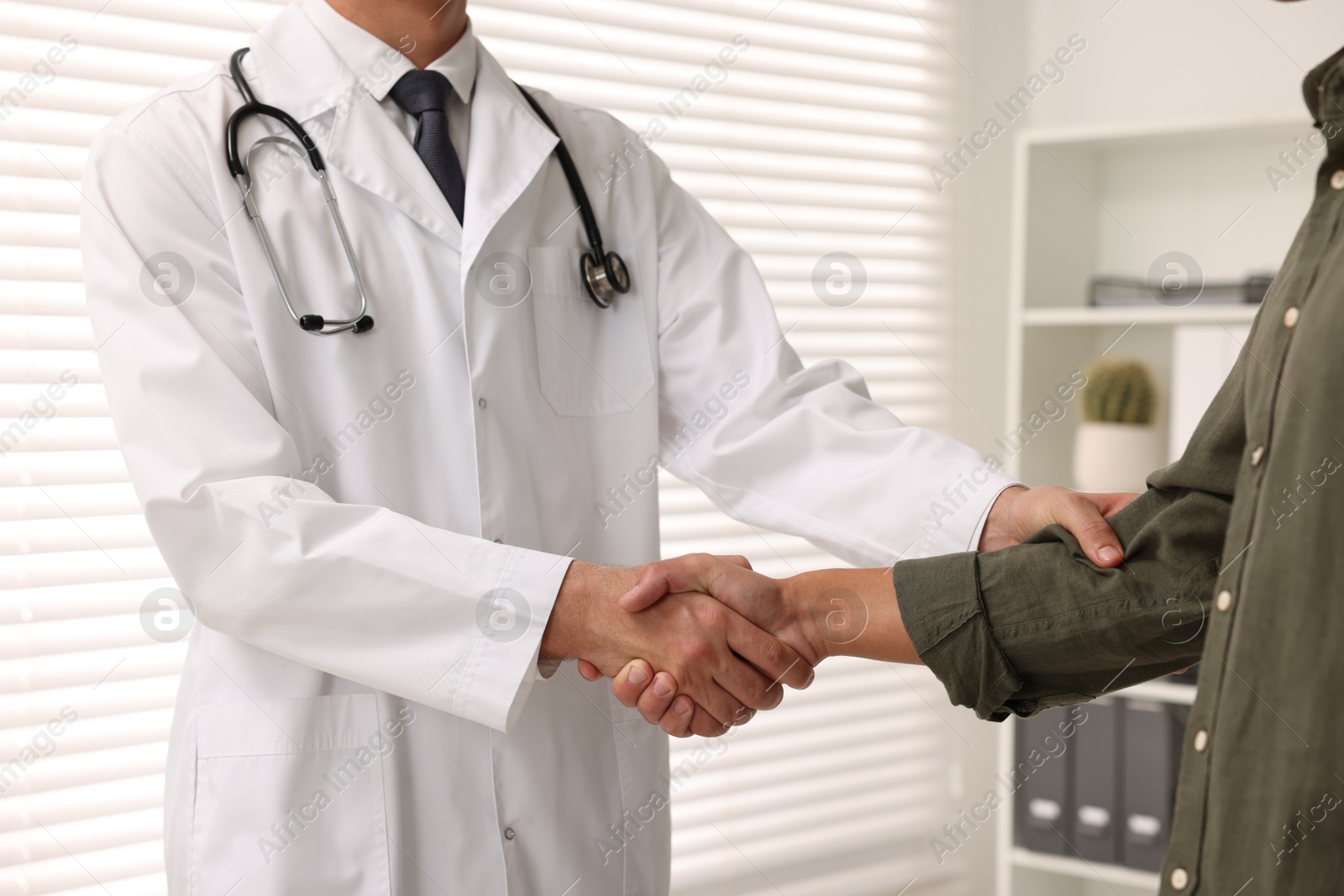 Photo of Doctor shaking hands with patient in hospital, closeup