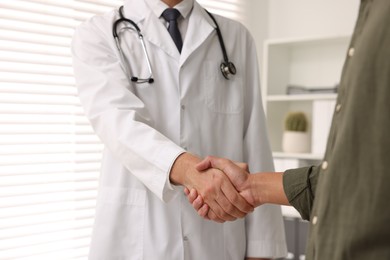 Photo of Doctor shaking hands with patient in hospital, closeup