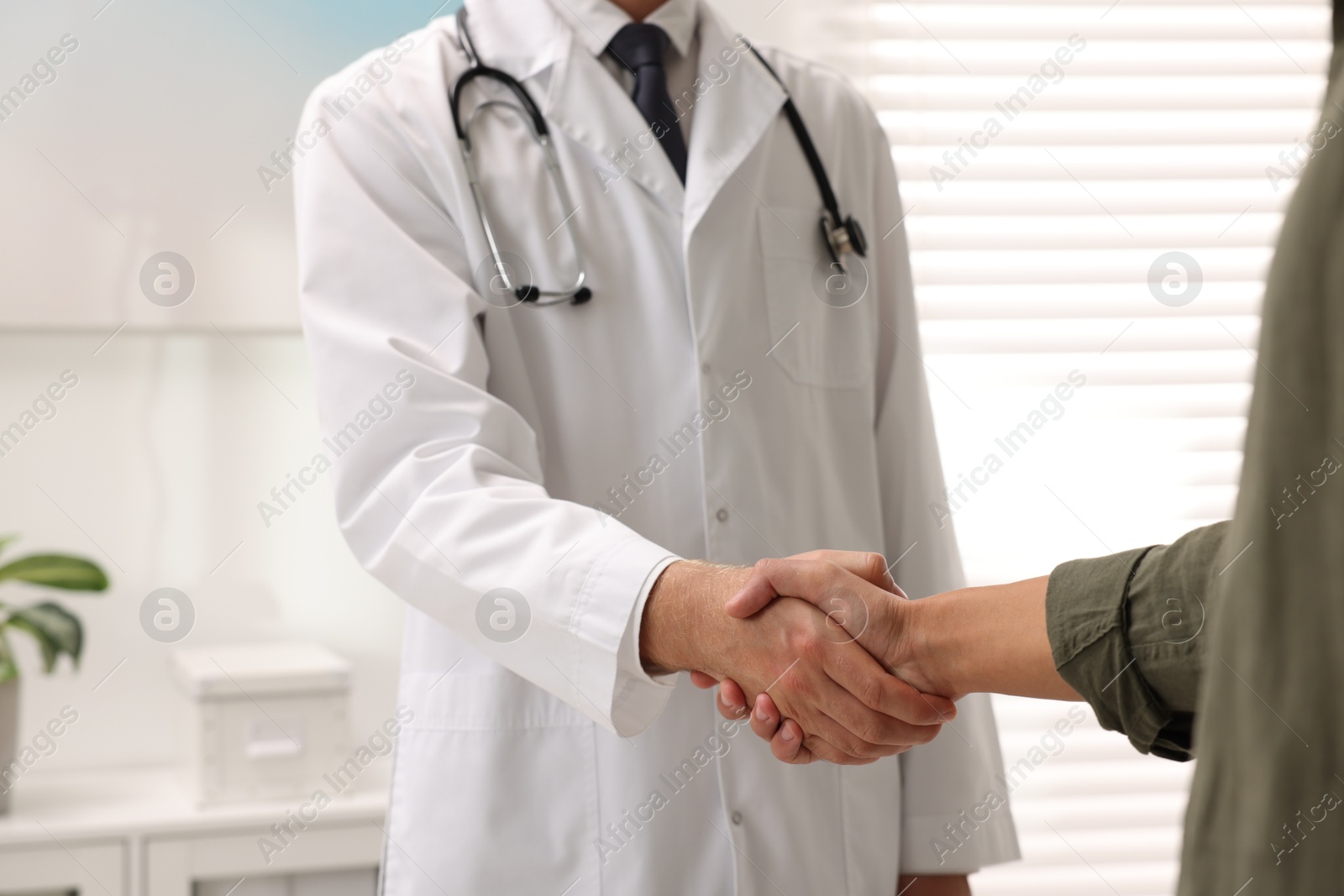 Photo of Doctor shaking hands with patient in hospital, closeup