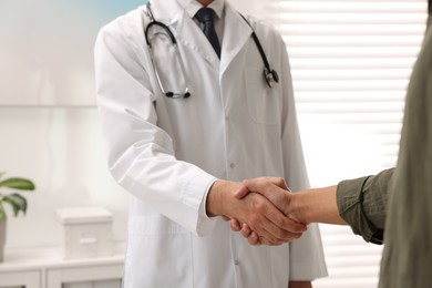 Photo of Doctor shaking hands with patient in hospital, closeup