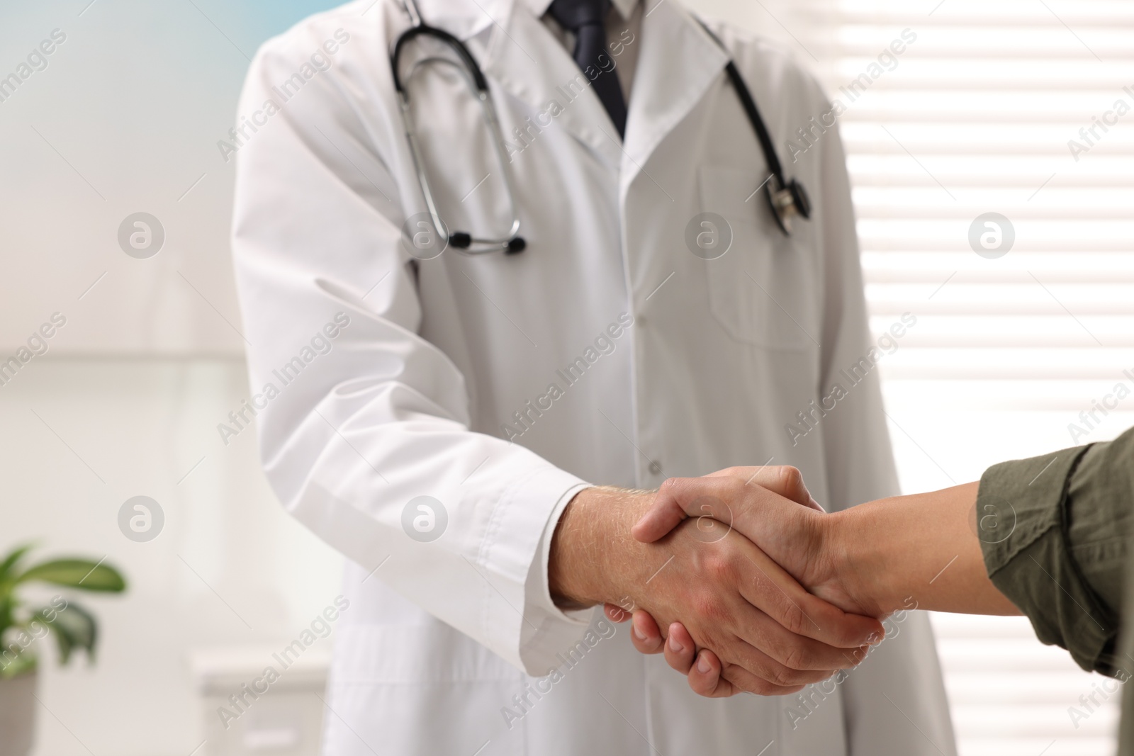 Photo of Doctor shaking hands with patient in hospital, closeup