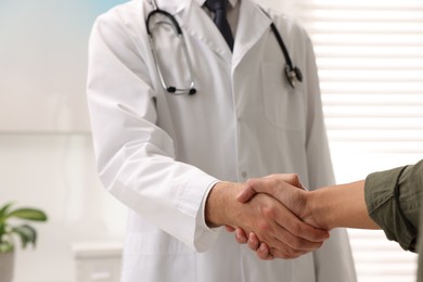 Doctor shaking hands with patient in hospital, closeup