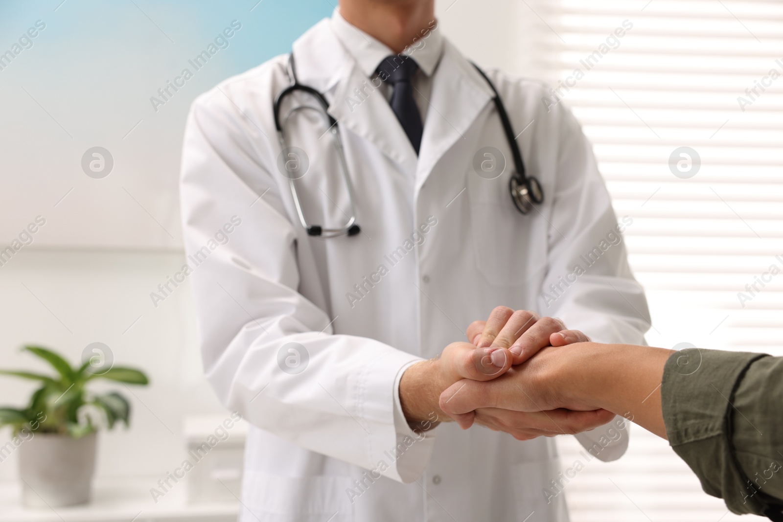 Photo of Doctor shaking hands with patient in hospital, closeup