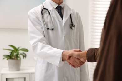 Photo of Doctor shaking hands with patient in hospital, closeup