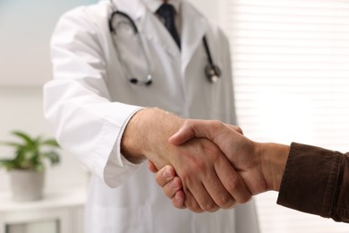 Doctor shaking hands with patient in hospital, closeup