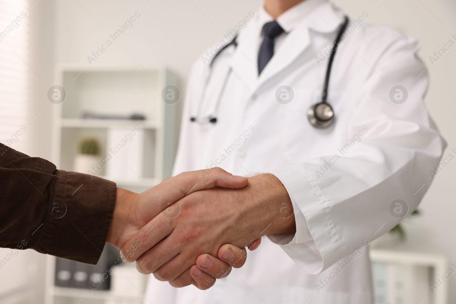 Photo of Doctor shaking hands with patient in hospital, closeup