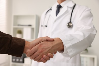 Doctor shaking hands with patient in hospital, closeup