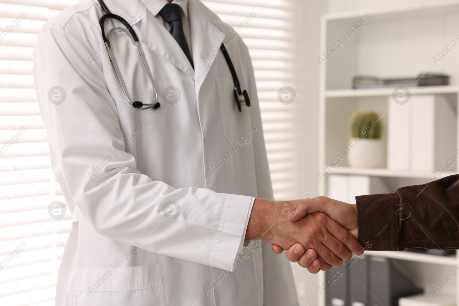 Photo of Doctor shaking hands with patient in hospital, closeup