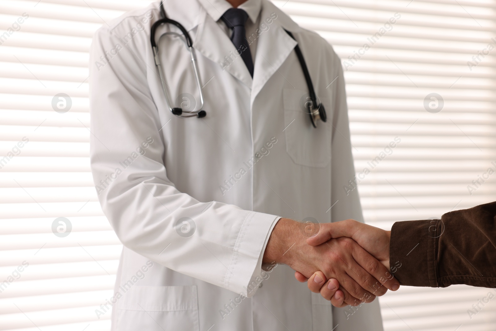 Photo of Doctor shaking hands with patient in hospital, closeup