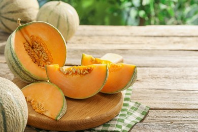 Photo of Ripe Cantaloupe melons on wooden table outdoors, space for text