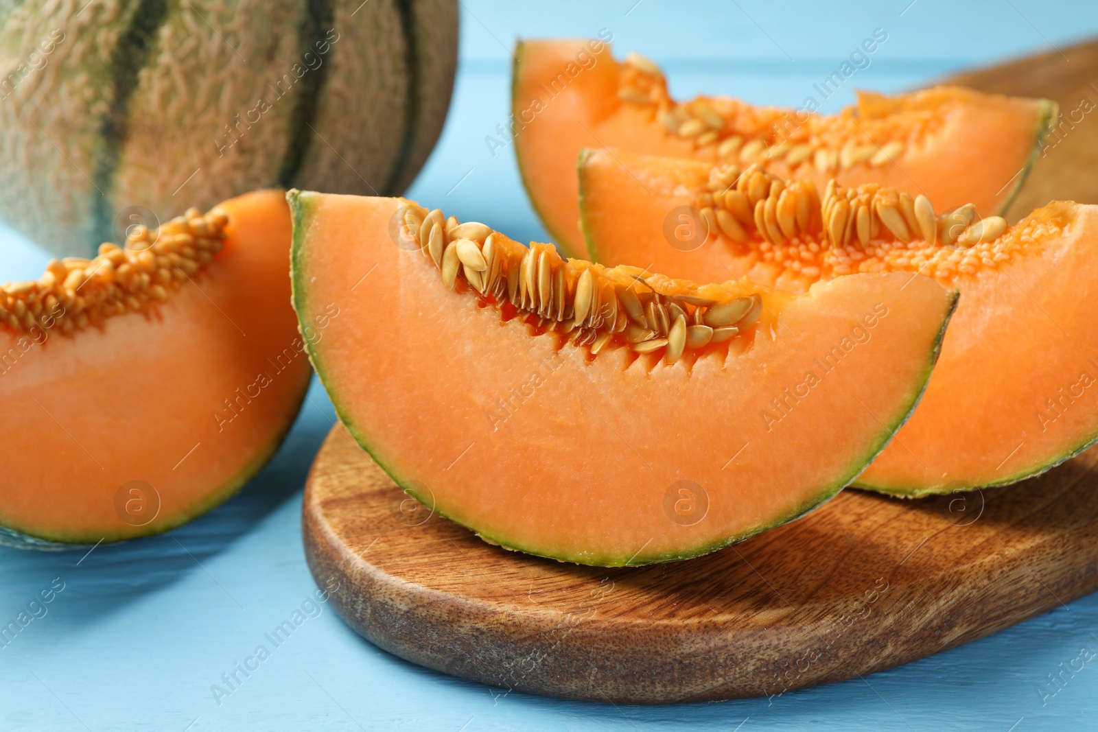 Photo of Tasty ripe Cantaloupe melon on light blue table, closeup