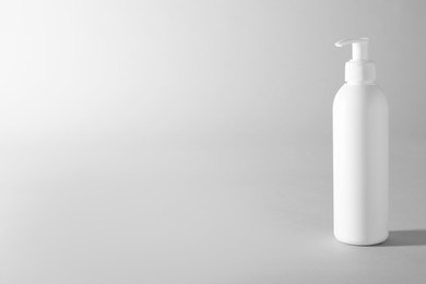 Photo of Shampoo in bottle on grey background, space for text