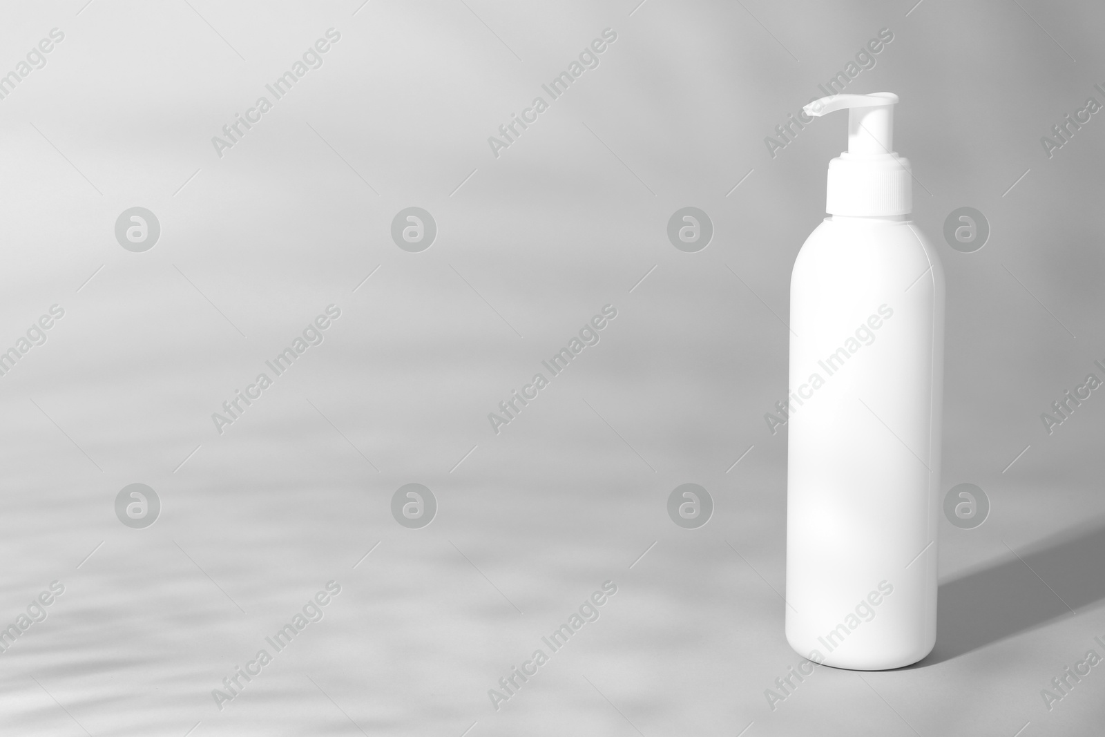 Photo of Shampoo in bottle on grey background, space for text