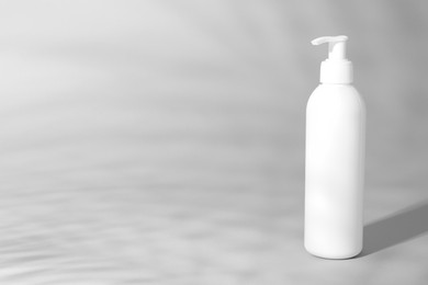 Photo of Shampoo in bottle on grey background, space for text