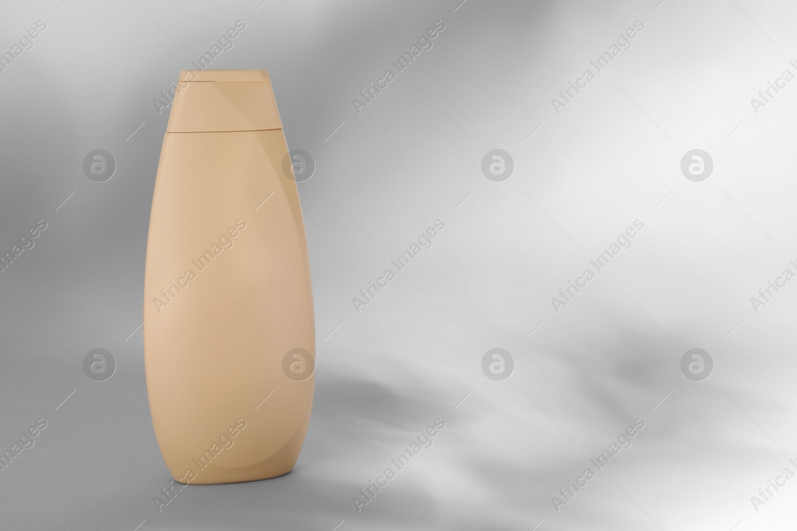 Photo of Shampoo in container on grey background, space for text