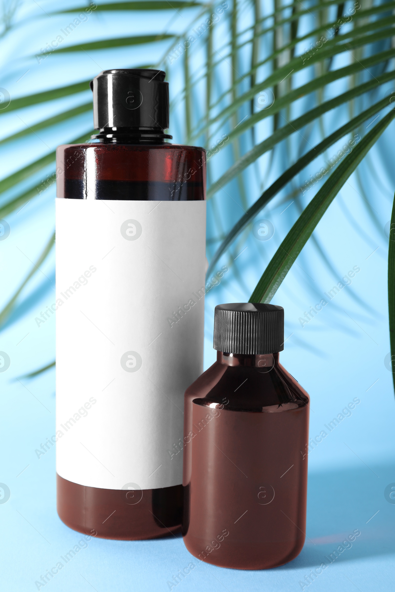 Photo of Shampoo in bottles on light blue background