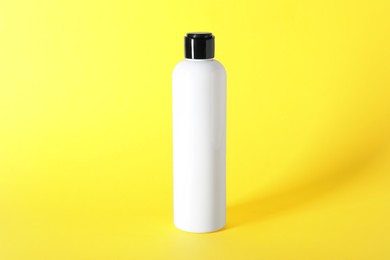 Shampoo in bottle on yellow background. Personal care product