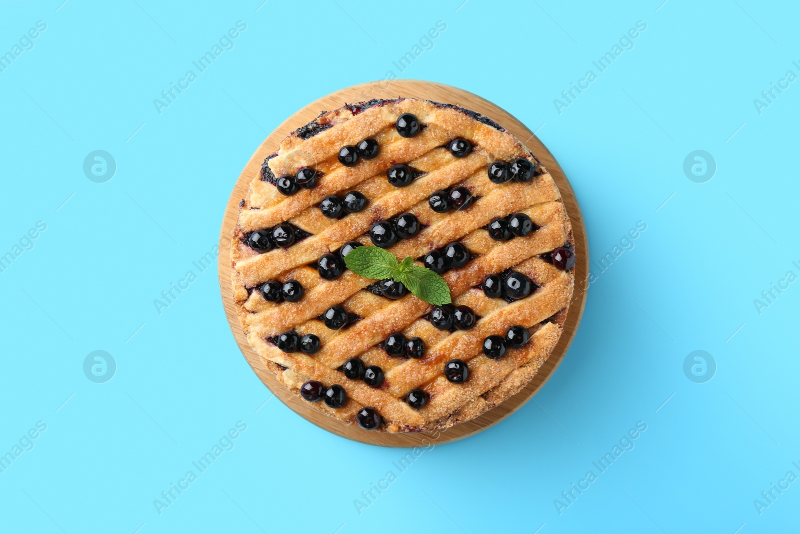 Photo of Delicious homemade blueberry pie with mint on light blue background, top view