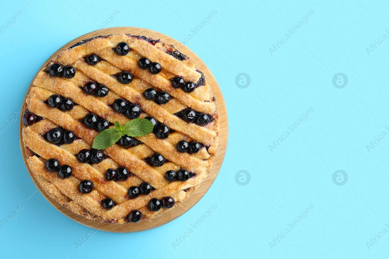 Photo of Delicious homemade blueberry pie with mint on light blue background, top view. Space for text