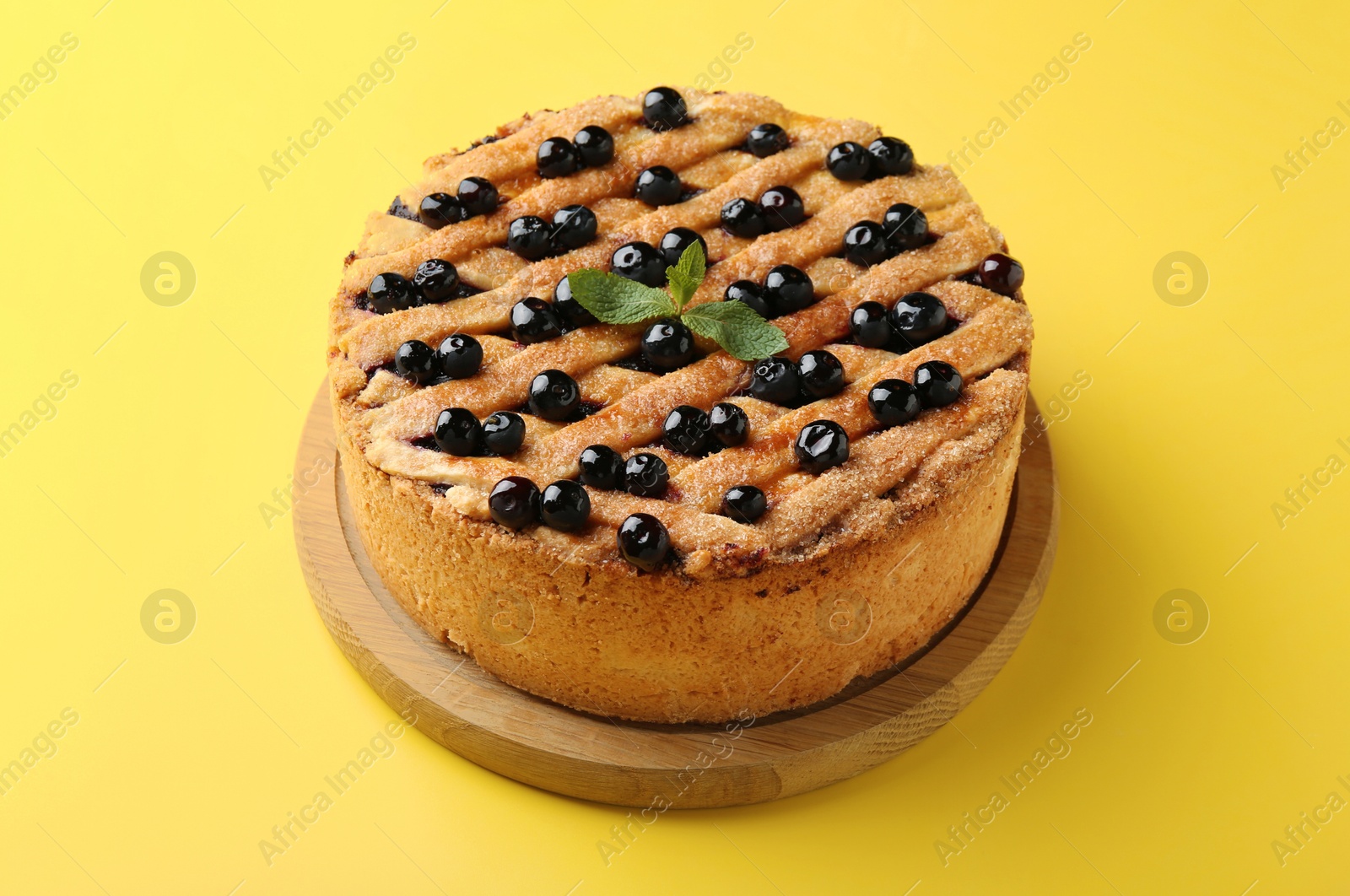 Photo of Delicious homemade blueberry pie with mint on yellow background