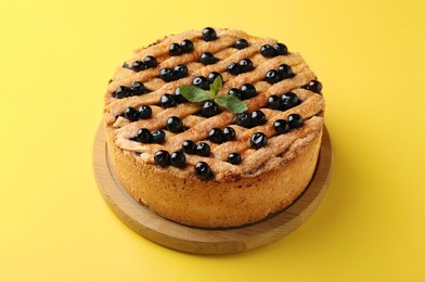 Photo of Delicious homemade blueberry pie with mint on yellow background