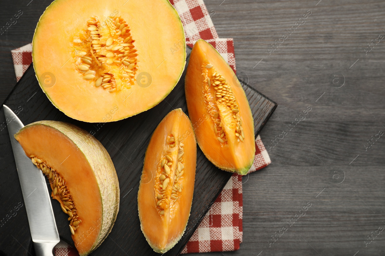 Photo of Fresh ripe Cantaloupe melon and knife on dark wooden table, flat lay. Space for text