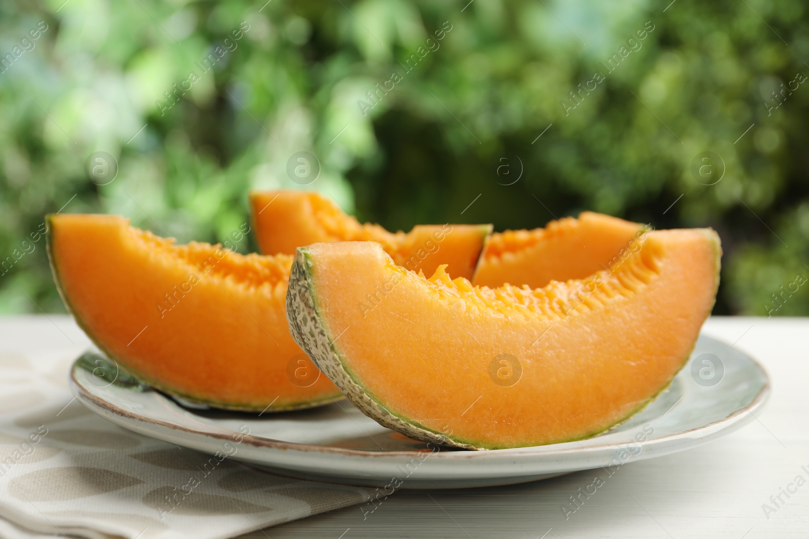 Photo of Pieces of fresh Cantaloupe melon on white wooden table, closeup