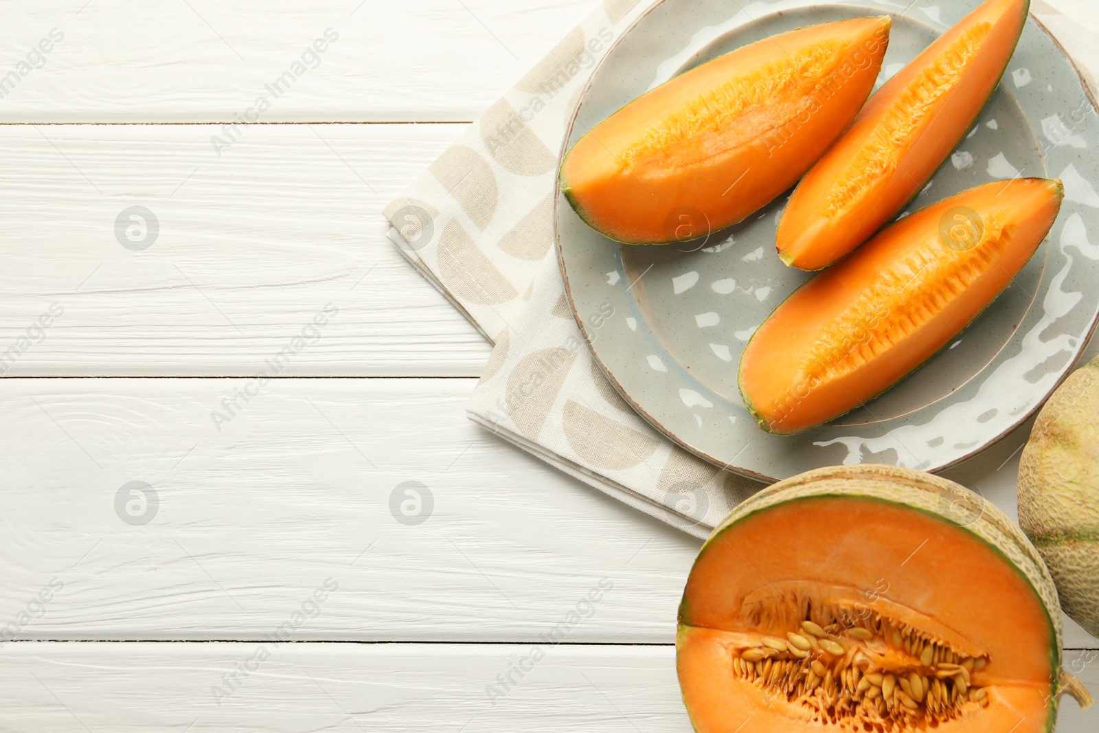 Photo of Pieces of fresh Cantaloupe melon on white wooden table, top view. Space for text