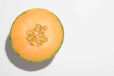 Photo of Half of fresh Cantaloupe melon on white table, top view. Space for text