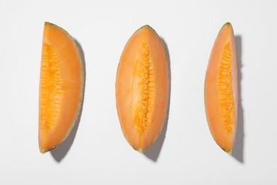 Photo of Pieces of fresh Cantaloupe melon on white table, flat lay