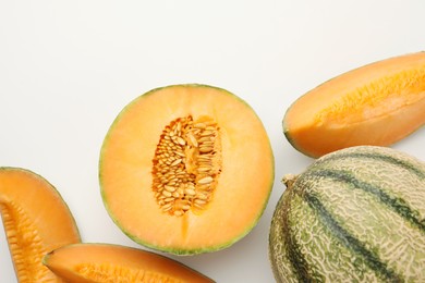 Photo of Cut and whole Cantaloupe melons on white table, flat lay