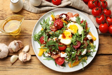 Photo of Tasty salad with arugula, egg, cheese and vegetables on wooden table, flat lay