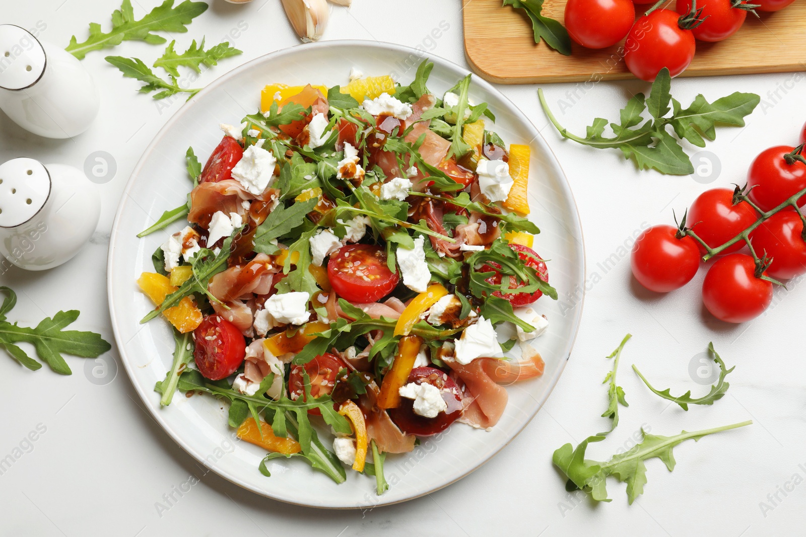 Photo of Tasty salad with arugula, cheese and vegetables on white table, flat lay