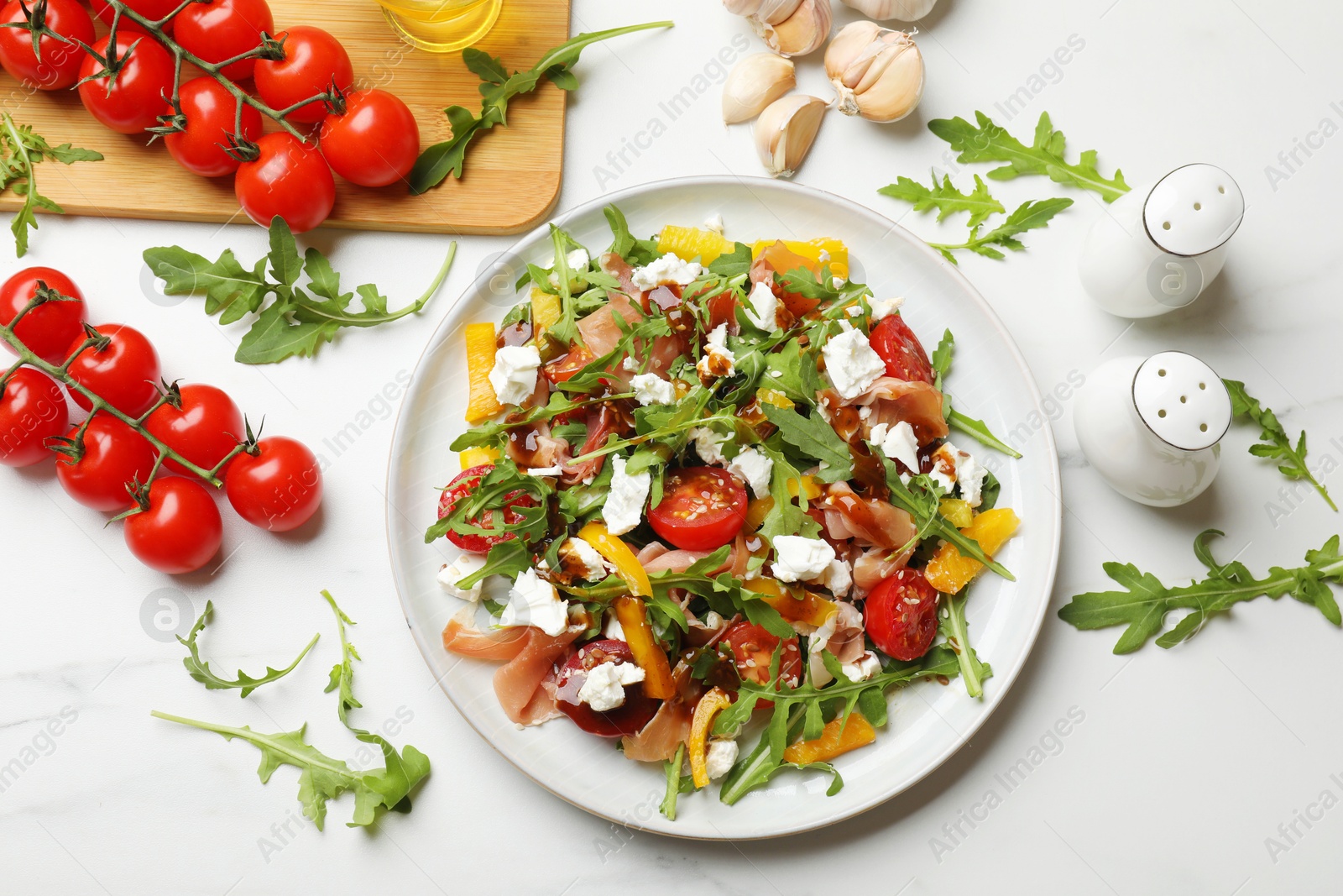 Photo of Tasty salad with arugula, cheese and vegetables on white marble table, flat lay