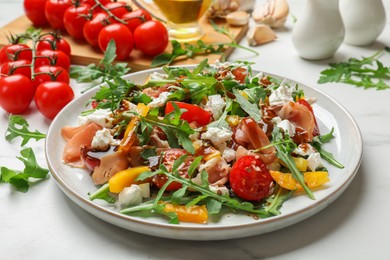 Photo of Tasty salad with arugula, cheese and vegetables on white table, closeup