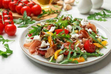 Photo of Tasty salad with arugula, cheese and vegetables on white table, closeup