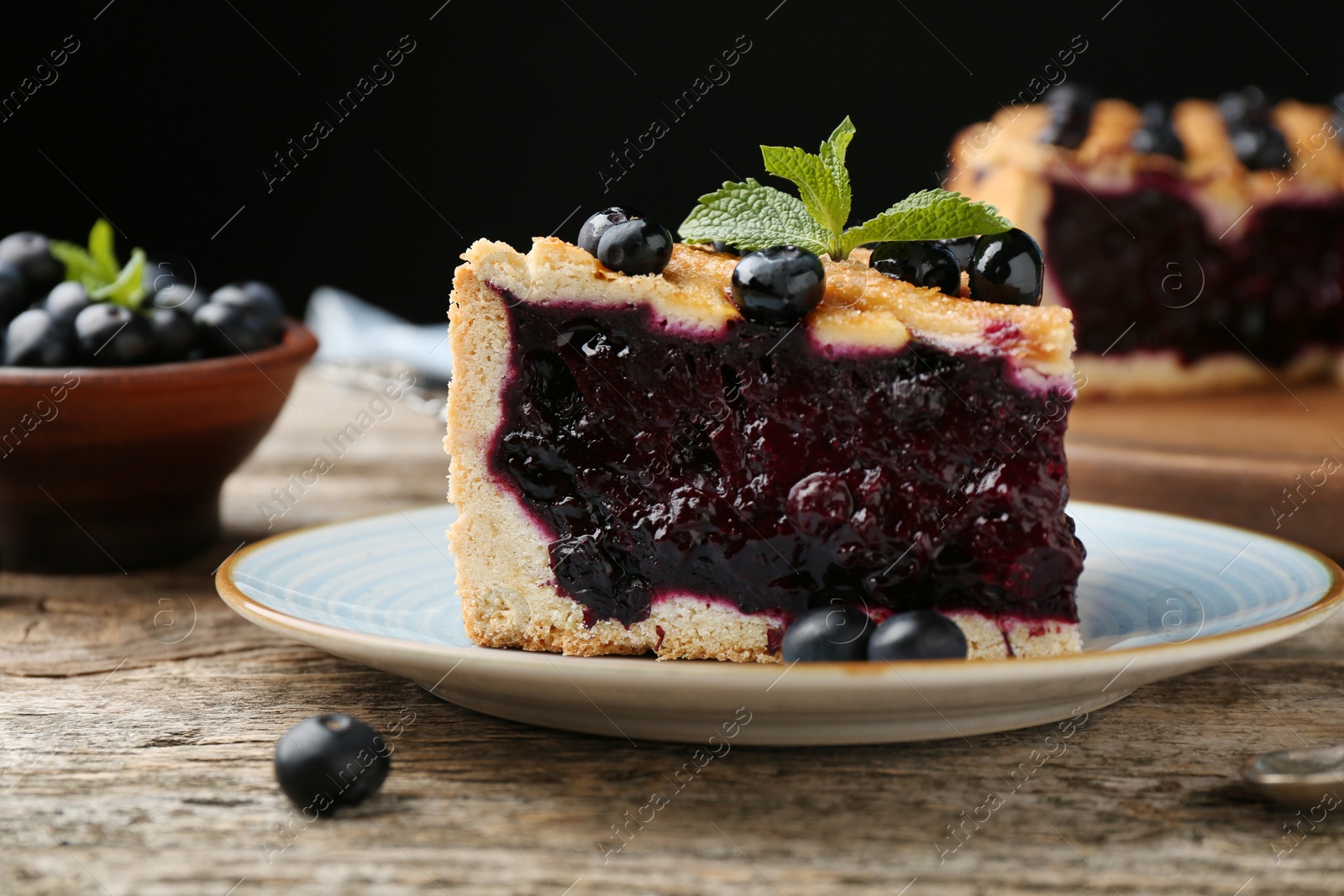 Photo of Slice of homemade blueberry pie on wooden table, closeup