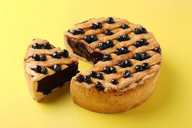 Photo of Cut homemade blueberry pie on yellow background