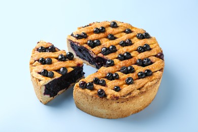 Photo of Cut homemade blueberry pie on light blue background