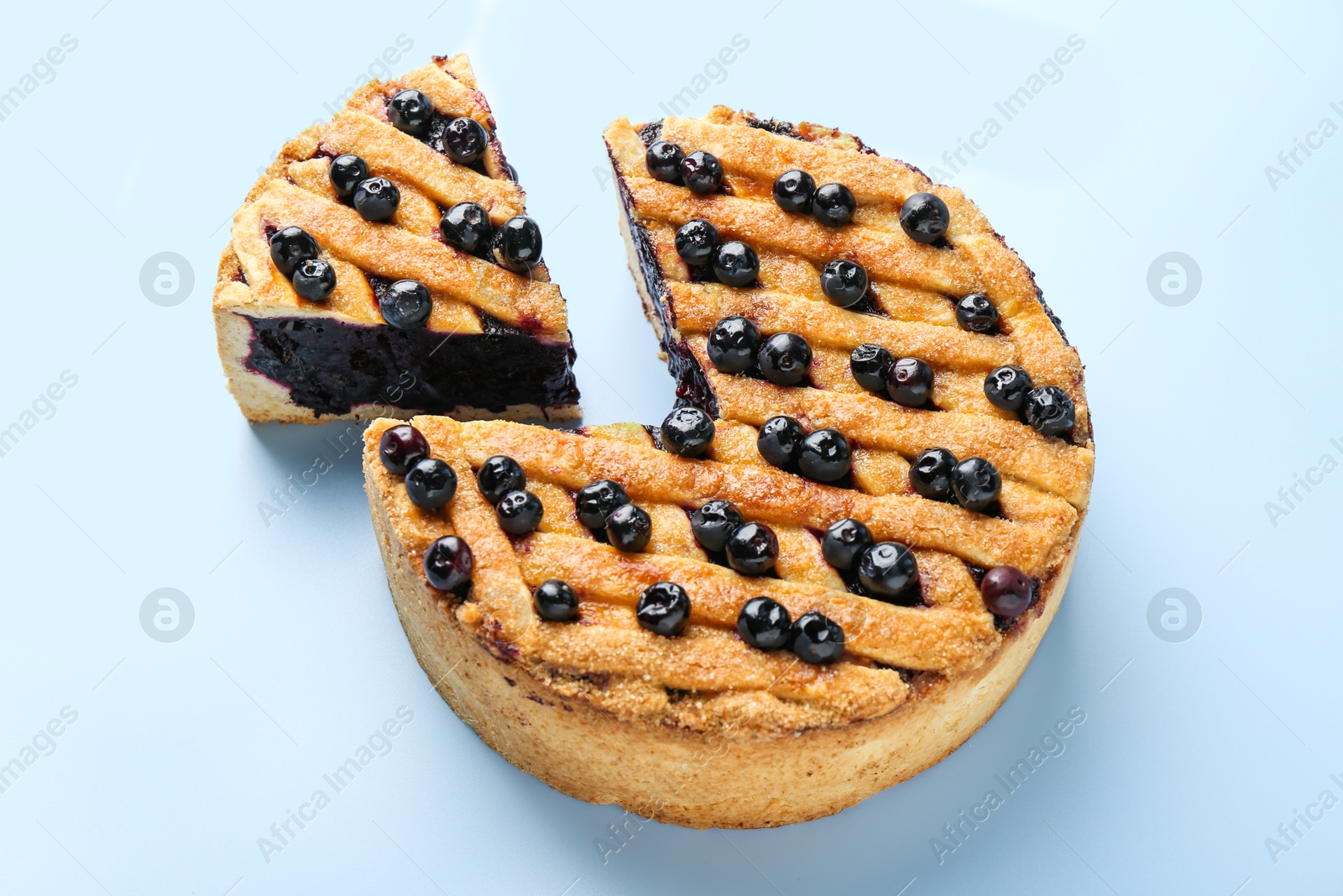 Photo of Cut homemade blueberry pie on light blue background